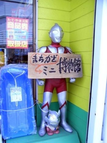 小学生くらいのウルトラマン。<br>首から博物館の看板をかけています。