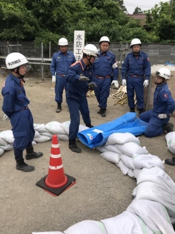 簡易水路の設営時の重要ポイントを署員の方から教わっている様子です。