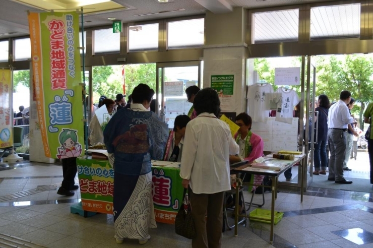 この日は天気が心配されていましたが、少しずつ明るい日差しが・・<br>そして恒例の朝市での、かどま地域通貨「蓮」の購入風景♪♪<br>蓮ちゃんの商品も、蓮ちゃん煎餅や、蓮ちゃんキャンディと販売しています!!