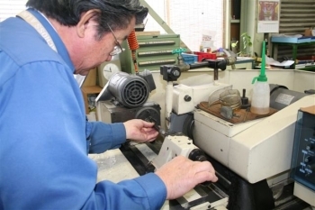 円筒研削機を操作する竹内さん。手の感触で微妙な調整を行います。