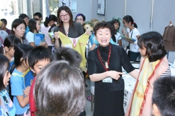 代表の女の子が栗田さんデザインの洋服プリントのついたエプロンを身に付けました