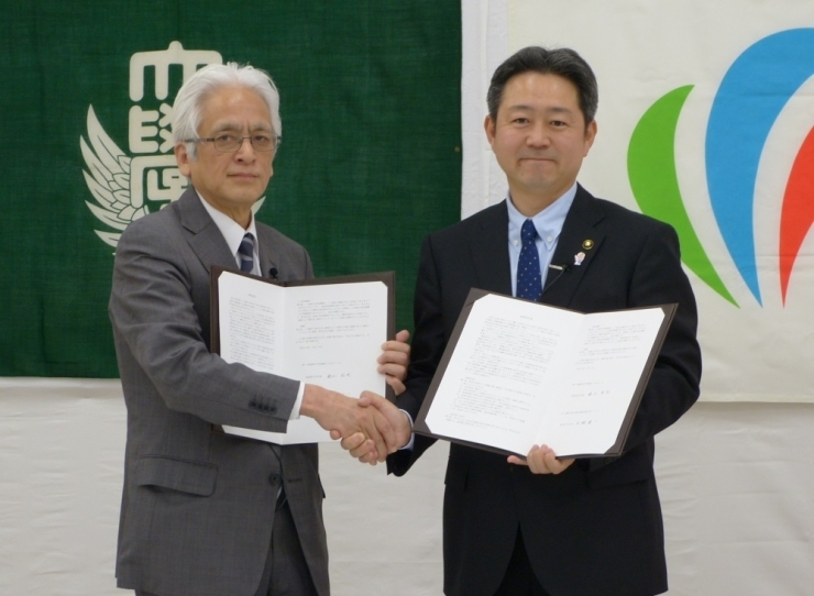 専修大学副学長　坂本武憲氏（左）と　行方市長　鈴木周也氏（右）が連携協定書に署名しました。