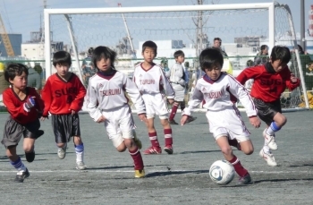 予選リーグで菅FC（赤ユニホーム）からボールを奪いゴールに突進する鶴見東FC＝12月23日