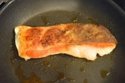 【2】フライパンにオリーブオイルを熱し、鮭の皮面を下にして並べ、弱めの中火で焼く。<br>いい焼き色が付き、上の方まで白っぽく火が通ったら、裏返して、弱火でじっくり中まで焼く。<br>一旦取り出す。