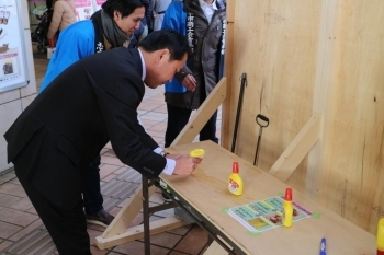 廃棄となったマカロンを使って、裏にボンドを塗ってボードに貼ります。<br>香川市長もボンドで手作業。