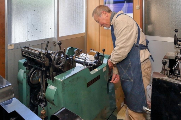 活版印刷機（DELLMAX 黒沢印刷精機）を操作する佐々木さん