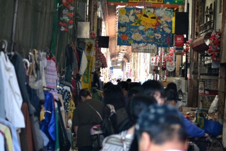 フリーマーケットなどが行われ、人の群れに囲まれにぎわいを見せる幸福本通商店街。