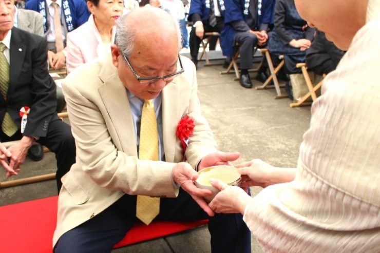 お茶をうける男性。来賓、関係者の方々からお饅頭とお抹茶が振舞われます。<br>