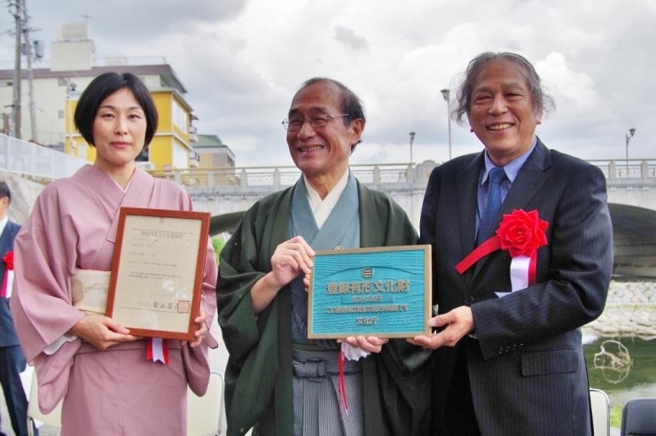 登録有形文化財のプレートを手に、門川市長を囲む小林氏（向かって左）、酒谷氏。