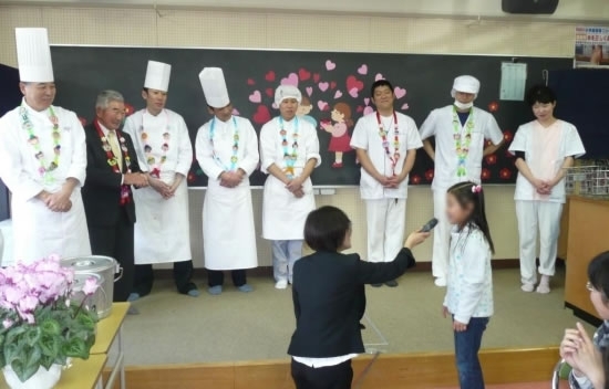 低学年の児童から、お礼の言葉を受ける小林さん（左端）と料理を作った人たち