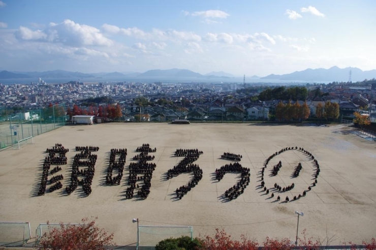11月14日（水）五日市高校グランド<br><br>東日本大震災復興支援ボランティア活動の一環として<br>全校生徒950名による　人文字　『顔晴ろう』を作りました。<br><br>※顔晴ろう　＝　津波で校舎を襲われた宮城県農業高校（名取市）の復興スローガン<br><br>この写真は　台紙に貼り付け　メッセージボードにする。<br>（復興を願う全校生徒の思いと共に・・・）<br>-------<br>11月25日~28日の予定で　生徒代表の13名が<br>額に入れたボードを持って　宮城県に訪問する予定。<br><br>