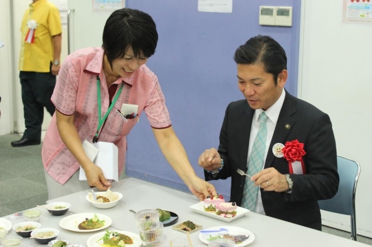 説明を受けながら商工会議所担当者から受賞作品の試食を勧められる松本市長