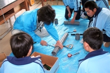 講師から配管材料のパイプの切り方を学ぶ生田中生徒。
