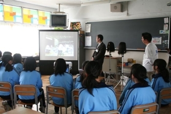 ビデオを見ながら理容競技会の説明を聞く生田中生徒。