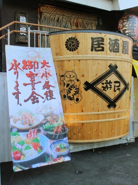 ▲高尾街道から目立つ「居酒屋 遊民」の樽飾り。