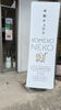 お店外観と看板タペストリー「6/11延長営業18時まで！岡山市中区、東岡山駅北口すぐ、米粉チュロス専門店」