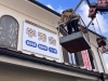 看板にシール貼り付け中「ついに看板設置‼️」
