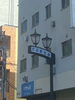都内某所、「詐欺被害調査」現場に向かう途中の商店街です。「1995年の創業から育んだ確かな探偵力で必ず「あなた」の抱えたお悩みを解決致します。無理な営業は一切致しません。ご安心下さい。」