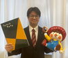 マルマンアート学院学院長代理・田中章朗。学院のキャラクター・かしびまると一緒に「新名称「マルマンアート学院」としての新たな決意をインタビューでお届け！」