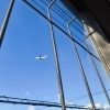 格子のすき間から見上げる、旅客機のお腹と青い空