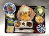 「鶏の照り焼き温玉のせにお刺身や多彩な小鉢が並ぶ家庭的でほっとする本日の日替わりランチ」