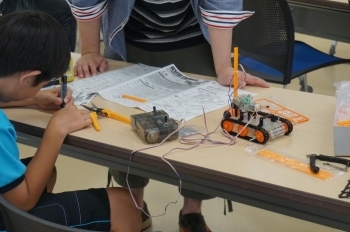 ロボット講座。ロボットを組み立て、もっと学びたい子はロボットを動かすプログラミングも教えてもらえます。大学生がお手伝いしてくれています。