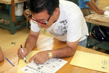 自分で描けない子の銀の板に図案を写し取る久保田先生。