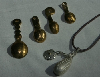 鎚目がついた真鍮製のスプーン（上）と蓮蕾形の銀のペンダント（下）