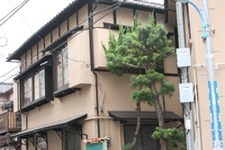 ちょうど曲り角に、稽古場と「東京神楽坂組合」の表札が掛かった建物（左）が並んでいます。間に立派な松（？）の木が。