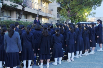 部活終わりに校門前で歌っている様子。周りに下校途中の生徒がたくさんいますが、お構いなしで堂々と歌っています。