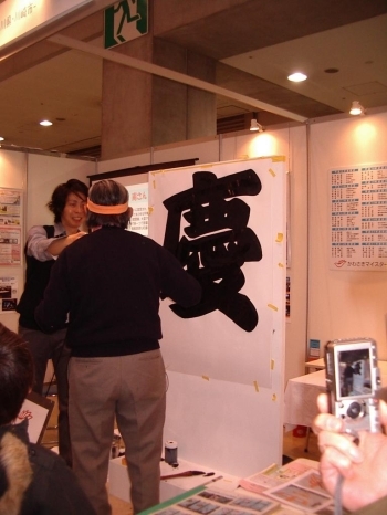 相撲文字の「慶」を書き終えた浅水屋さんにスタッフが説明を求めます。