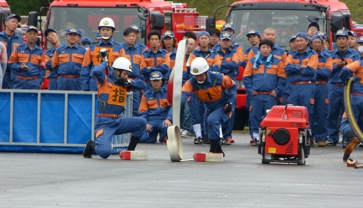 各地区の消防団が見守る中、競技が始まります。　競技中はホースの擦れる音と選手の走る音、号令の音！　