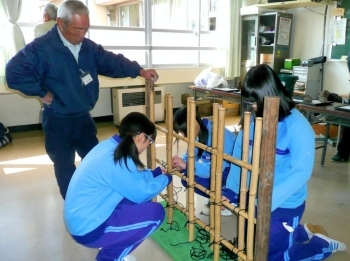 マイスター・井上さんの助言を受けながら「四つ目垣」つくりをする東高津中学校の生徒たち