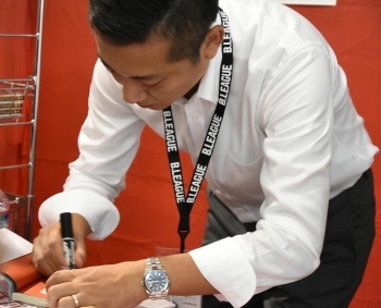 関東アーリーカップで、ブースターからのリクエストに応えて著書にサインをする島田代表。