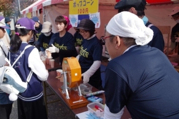 【皆山学区】<br>ポップコーンを販売するのは皆山学区の皆さん。ガラガラを回して運がよければサービスする仕掛け。「当たり出ろ！」飛び出した玉を見守る皆さん。