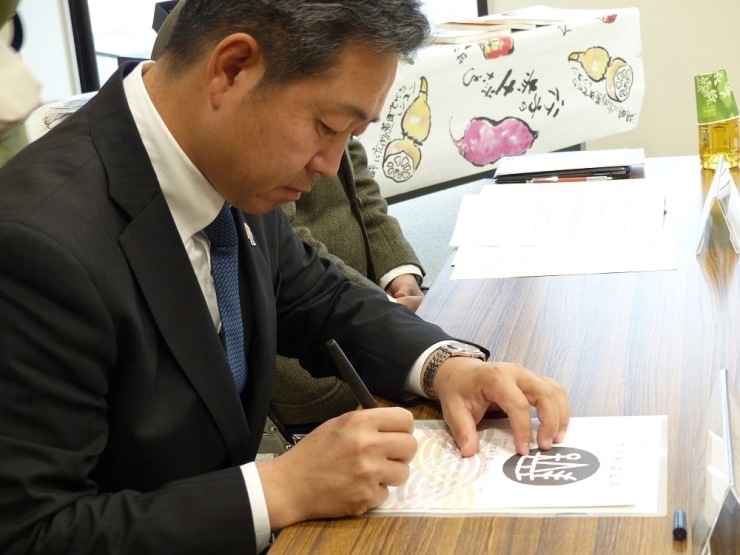 認定証管理者としてサインをする鈴木市長。　