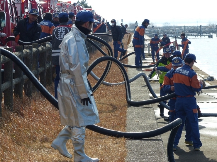 天王崎公園駐車場から霞ヶ浦に向けて一斉放水をします。放水担当以外の団員は準備に取り掛かります。