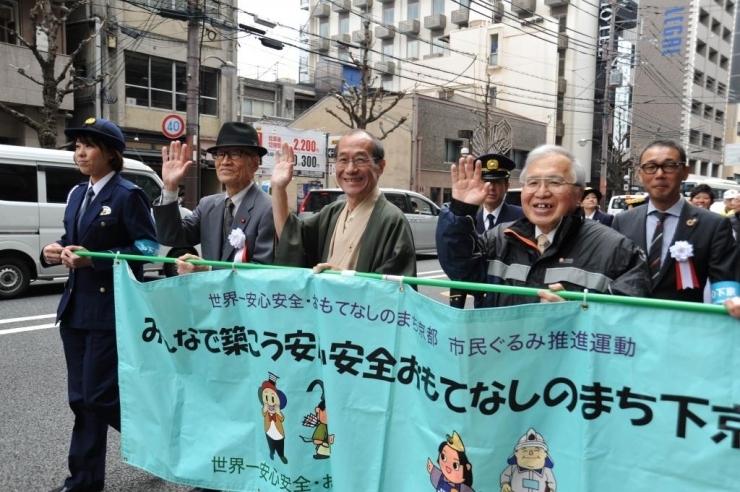 横断幕「みんなで築こう安心安全おもてなしのまち下京区」を掲げてパレード<br>（写真左手より、鎌田委員長、門川市長、藤岡会長、安河内区長）