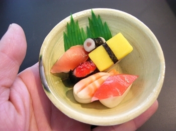 女将さんの手作り陶器に飾られた手<br>のひらにのる大きさが可愛らしい「雛寿司」。<br>もちろん和菓子です。