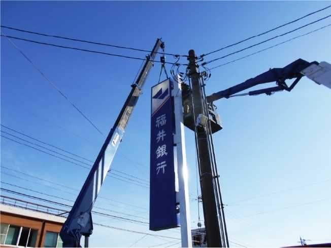 修繕後の看板を取り付けている場面「福井銀行村国支店の看板修繕」