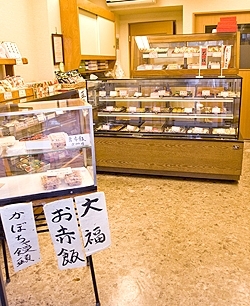 ショーケースに15～16種類のお菓子が並ぶ店内。お赤飯を販売しているのも町の和菓子屋さんらしい。
